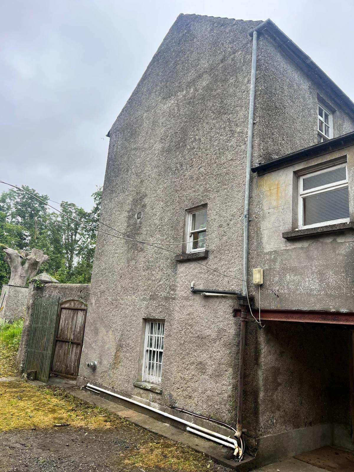 Period home in Cloughjordan with stained pebble dash walls and red algae growth before wall cleaning and coating by UEH Ireland.